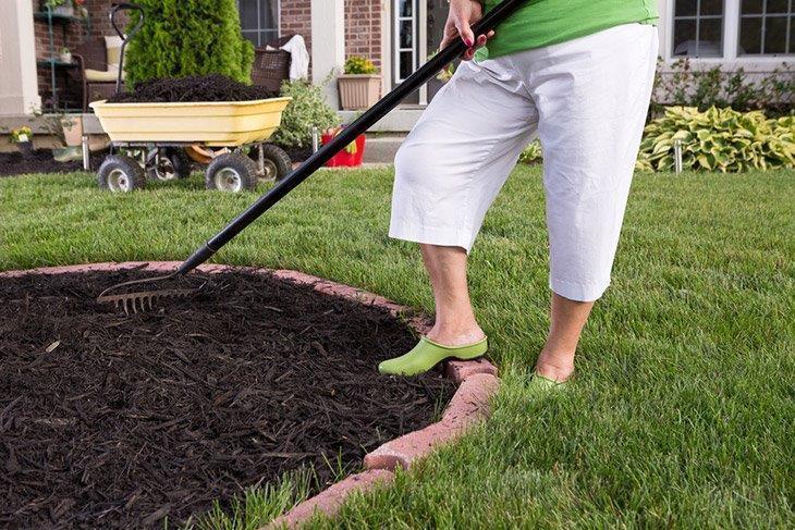 Woman spreading mulch in garden _How to kill dallas grass