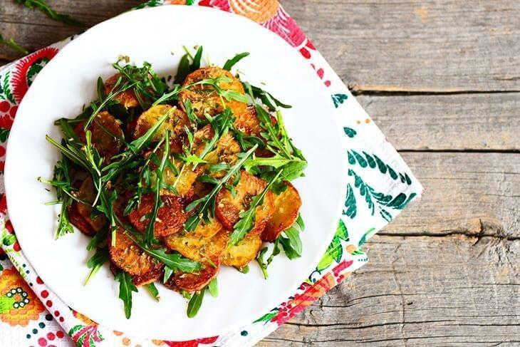 Roasted vegetables with Arugula on a wooden background