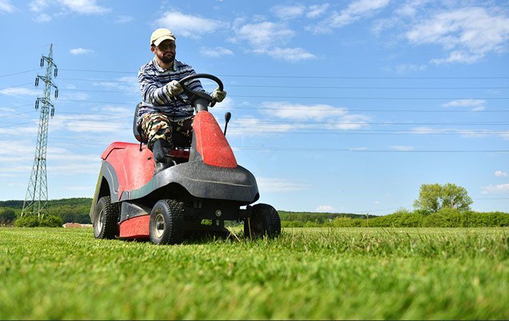 A gardener sitting on a riding lawn mower